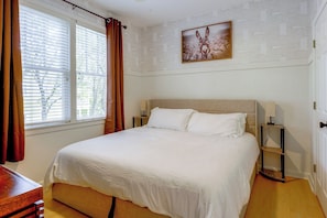 A bedroom with a bed, a nightstand, a lamp, and a window with curtains.