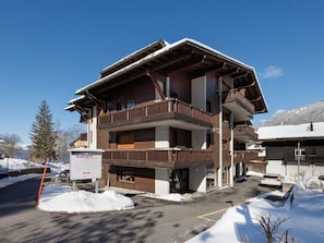 A multi-story building with balconies, a sign indicating a Vintners Experience, and snow on the ground. - Les Dryades 8 by Interhome (Villars)