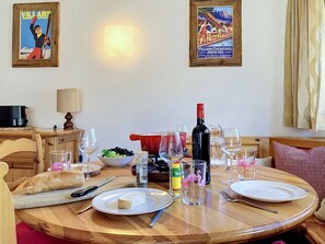 A dining table set with plates, wine glasses, and a bottle, surrounded by chairs and a lamp. - Les Dryades 8 by Interhome (Villars)