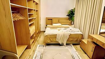 A bedroom with a bed, wooden wardrobe, and a ceiling light fixture.