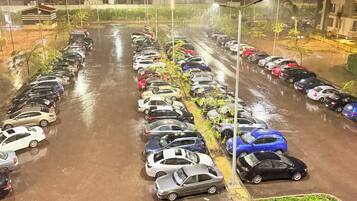A parking lot with multiple rows of parked cars, illuminated by overhead lights.