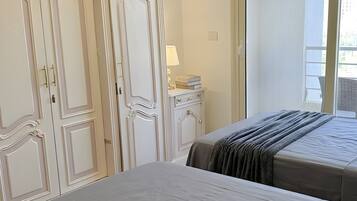 Une chambre avec deux lits, une commode, un miroir et une fenêtre.