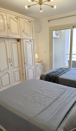 Une chambre avec deux lits, une commode, un miroir et une fenêtre.