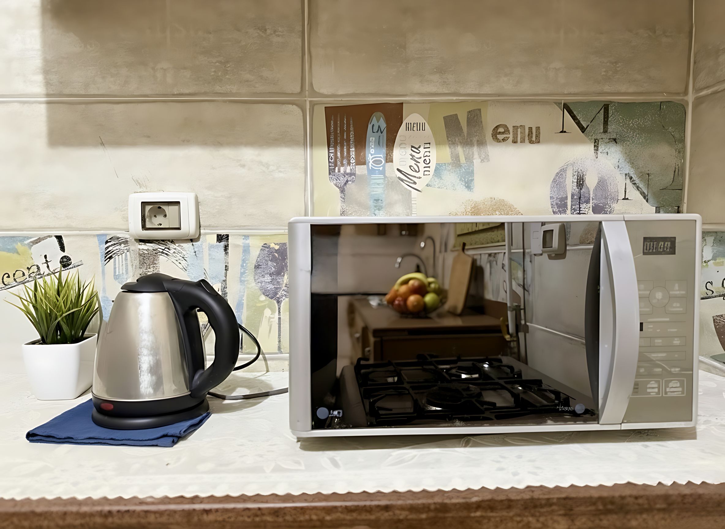A kitchen with a built-in microwave and stove, a kettle, and a potted plant on the counter.