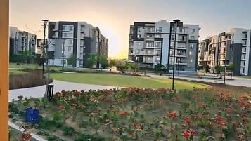 A residential area with modern apartment buildings, a grassy field, and a paved walkway.