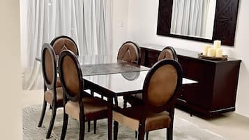 A dining area with a round table, six chairs, a dark wooden cabinet, and a chandelier.
