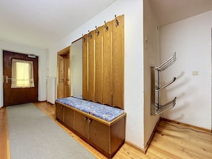A bedroom with a wooden wardrobe, a bench with a patterned cushion, a radiator, and a door with a curtain. - Ferienhaus Christl by Interhome (Pians)