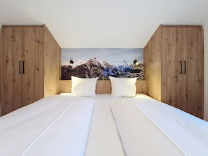 Une chambre à coucher avec un lit, une armoire en bois et un luminaire fixé au mur.