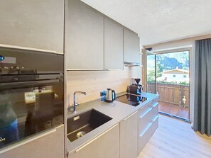 A modern kitchen with a built-in oven, a sink, and a coffee maker. - Kombi Edelweiss+Enzian by Interhome (Mayrhofen)