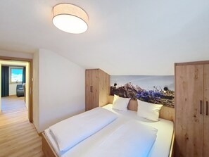 A bedroom with a bed, wooden wardrobe, and a wall mural. - Kombi Edelweiss+Enzian by Interhome (Mayrhofen)