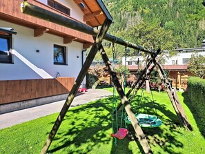 Et træsving i en velholdt have med en bygning i baggrunden.