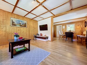 A wooden interior with a dining area, a TV mounted on the wall, and a painting on the wall. - Huus 115 by Interhome (Dalaas)