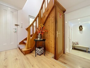 A wooden staircase with a vase of flowers, a bench, and a door with a coat of arms. - Huus 115 by Interhome (Dalaas)
