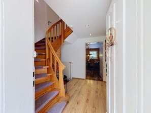 A staircase with wooden steps and a handrail, leading to a room with a radiator and a door. - Huus 115 by Interhome (Dalaas)