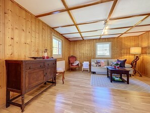 A wooden-paneled room with a sofa, a chair, a dresser, and a lamp. - Huus 115 by Interhome (Dalaas)