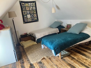 Une chambre avec deux lits, un bureau, une lampe et une tapisserie murale.