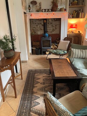 A cozy living room with a fireplace, a sofa, a coffee table, and a patterned rug.