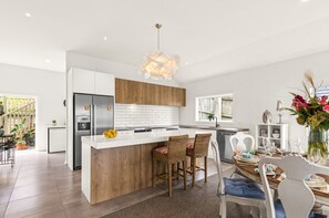 Une cuisine moderne dotée d’un îlot central, de meubles blancs et d’un mur d’accent en bois.