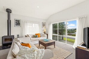 Un salon comprenant un canapé, une table basse, une cheminée et une grande fenêtre donnant sur un beau paysage.