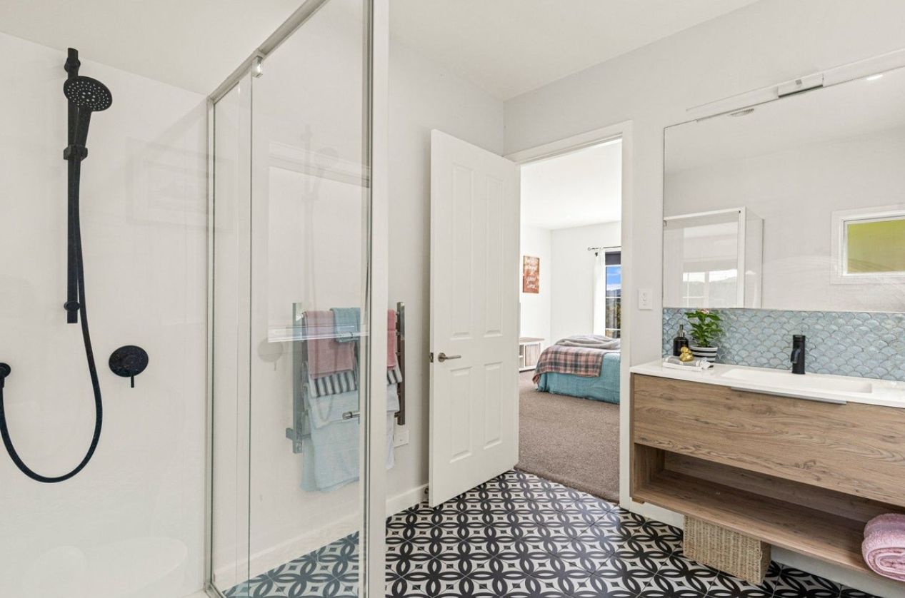 A bathroom with a shower, a mirror, and a sink.