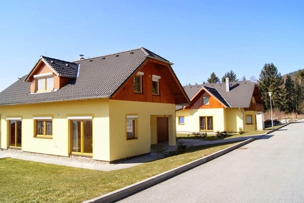 Une rangée de maisons à deux étages, dotées d’un toit en pente, d’un porche à l’avant et d’une pelouse bien entretenue.