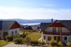 Un quartier résidentiel avec des maisons, un ciel dégagé et une étendue d’eau visible au loin.