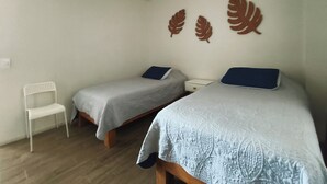 A bedroom with two single beds, a ceiling fan, and a white chair. - Acogedor y cómodo, gym, alberca seguridad 24 horas (Zapopan)