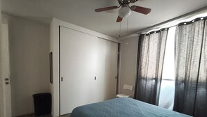 A bedroom with a bed, a ceiling fan, a window with curtains, and a door. - Acogedor y cómodo, gym, alberca seguridad 24 horas (Zapopan)