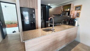 A modern kitchen with a built-in island, stainless steel appliances, and a microwave. - Acogedor y cómodo, gym, alberca seguridad 24 horas (Zapopan)