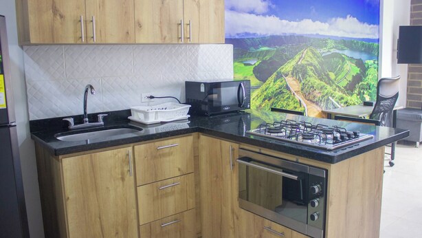 A kitchen with wooden cabinets, a black countertop, a microwave, a gas stove, and a dishwasher. - 41 September Promo in The Coolest Neighborhood (Medellín)