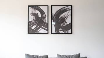 A grey sofa with two cushions and a remote control on a coffee table.
