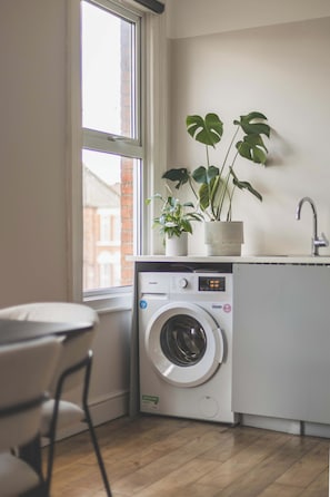 A compact laundry area with a washing machine, a sink, and a window. - Stylish 3BED flat, great location (Greater London)