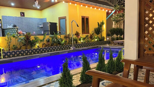 A pool area with a tiled floor, a wooden bench, and a kitchen area with a refrigerator and sink. - La Armber Hotel (Luang Prabang)