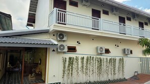 A two-story building with multiple air conditioning units, a balcony, and a tiled entrance. - La Armber Hotel (Luang Prabang)