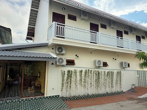 Ein zweistöckiges Gebäude mit mehreren Klimaanlagen, einem Balkon und einem gefliesten Eingangsbereich.