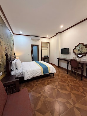 Ein Hotelzimmer mit Bett, Schreibtisch, Stuhl, Fernseher und Spiegel.