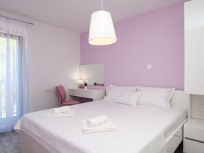 Ein Schlafzimmer mit einem Bett, einem Schreibtisch, einem Stuhl und einer Pendelleuchte.