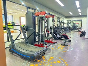 Ein Fitnessstudio mit Laufbändern, Krafttrainingsgeräten und einer Spiegelwand.