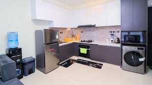 A compact kitchen with a refrigerator, oven, microwave, and washing machine. - Spacious 1-bedroom apartment in Westlands, Nairobi, Kenya (Nairobi)