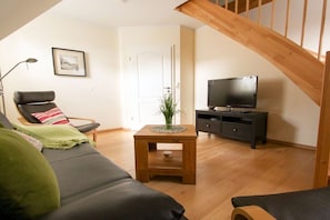 A living room with a sofa, a small wooden table, a television, and a staircase. - Holiday home in Zingst with swimming pool (Zingst)