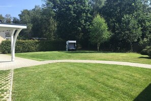 Een verzorgd gazon met een kiosk en een gebouwtje in de verte.