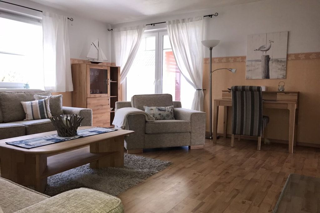 A living room with a sofa, armchair, wooden coffee table, and a lamp.
