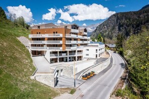 Ein mehrstöckiges Hotel mit Balkonen, einer gewundenen Straße und einer Bergkulisse im Hintergrund.