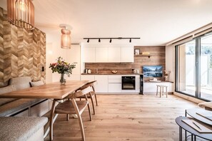 Cozinha moderna com armários de madeira, área de jantar com mesa e bancos de madeira, e uma grande janela que oferece iluminação natural.