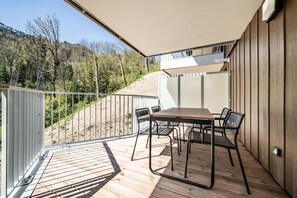 A balcony with a table and chairs, overlooking a forested hillside. - Houchma – Charming 4-Guest | Mt Blanc View | Spa | Lifts 400m (Les Houches)