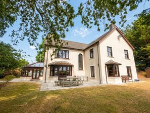 Une maison à deux étages avec un patio couvert, une pelouse et un ciel dégagé.