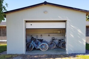 A garage with a white exterior, a brown roof, and a garage door. Inside, there are three bicycles parked. - Holiday apartment in Barth with swimming pool (Barth)