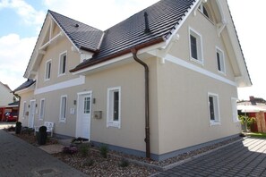 Ein zweistöckiges Haus mit beiger Fassade, einem Ziegeldach und einem Eingangsbereich mit Briefkasten.