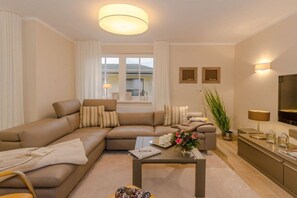 Ein modernes Wohnzimmer mit einem Ecksofa, einem Couchtisch und einem Fernseher.