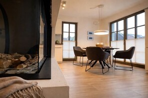 A modern interior with a fireplace, dining area, and large windows. - Holiday apartment with 2 bedrooms (Zingst)